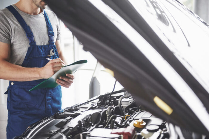 mec&aacute;nico revisando un checklist sobre el correcto funcionamiento del autom&oacute;vil, incluyendo el sistema de arranque de pendientes