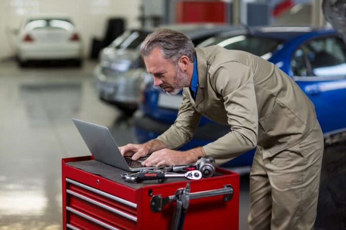 mec&aacute;nico haciendo un an&aacute;lisis en su laptop sobre el mantenimiento de auto
